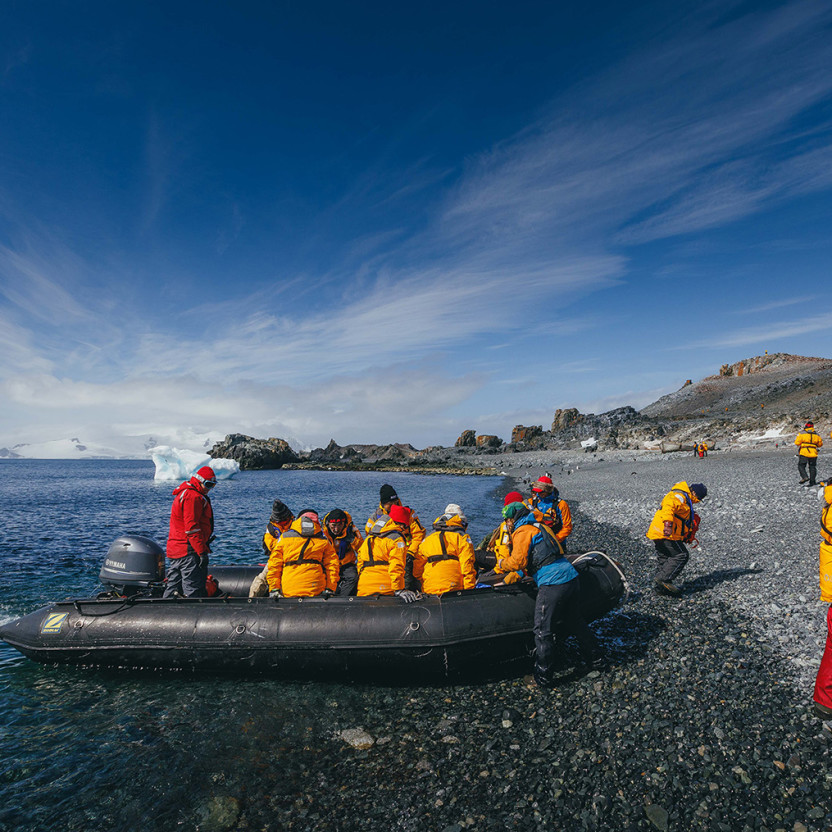 Expedition Guides help guests get out of their zodiac boats on a rocky beach at Half Moon Island.