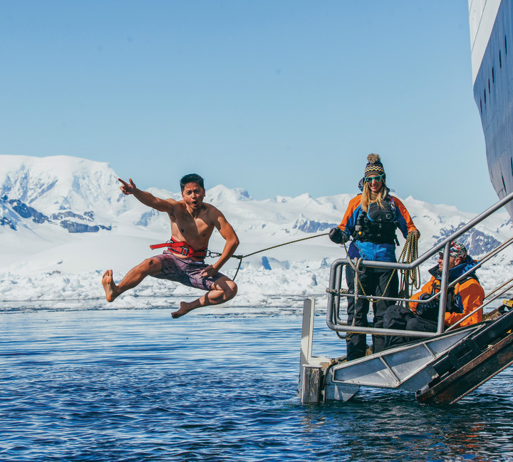 A guest jumps off the gangway (with a safety harness) into Antarctic waters during the Polar Plunge.