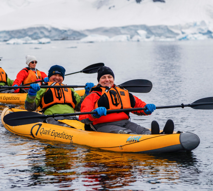 Two guests in dry suits paddle through Antarctic waters onboard our sit-on-top inflatable kayaks.