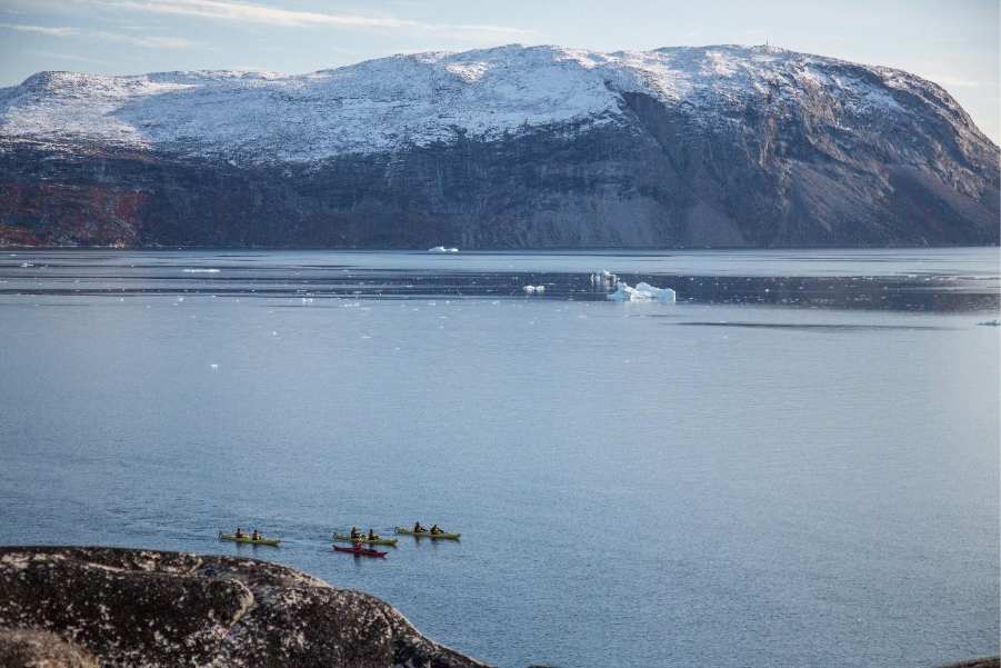 A group of adventurers kayaking ice covered mountains. 